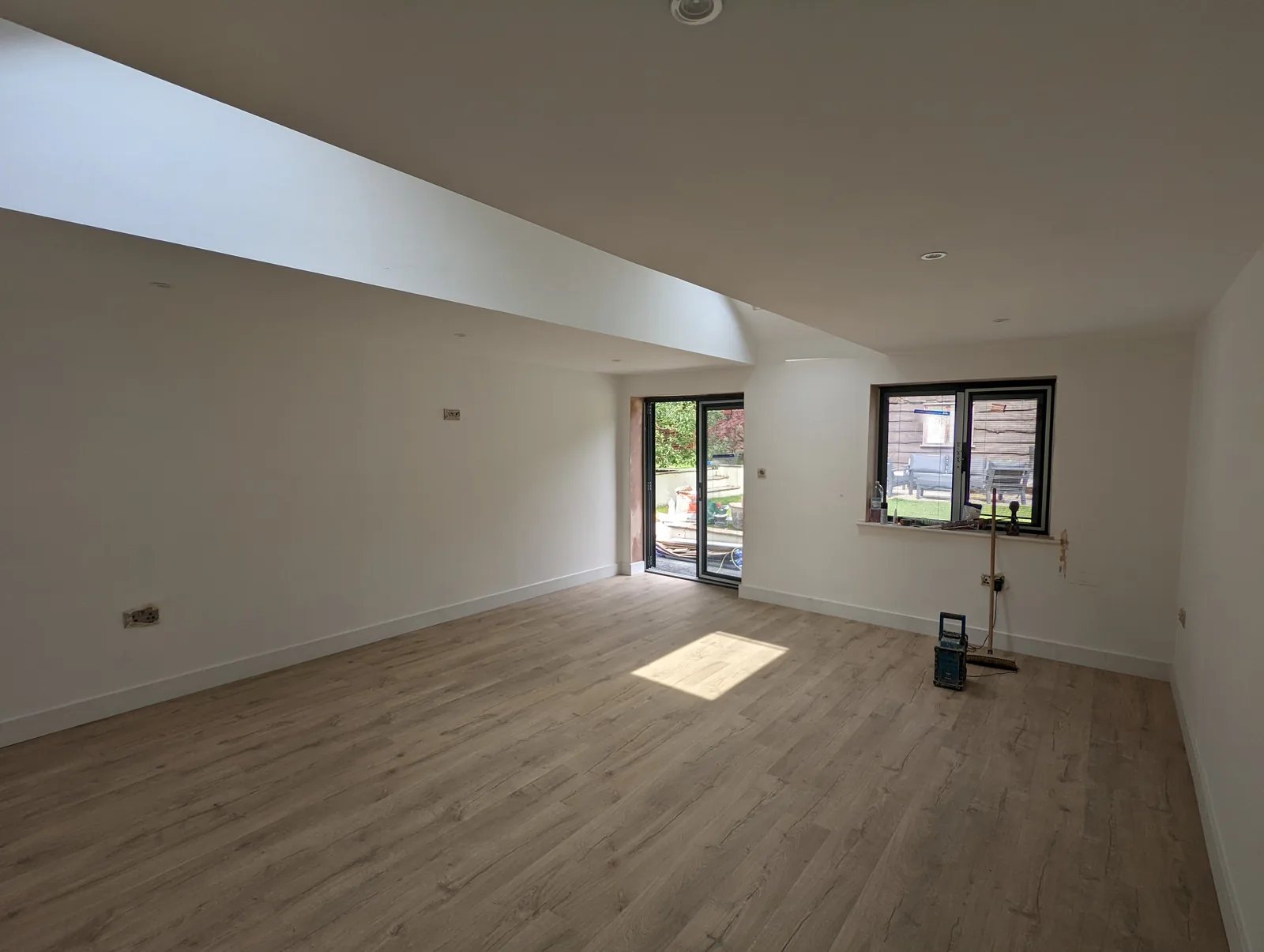 Bright conversion interior with a vaulted ceiling and garden doors, with final finishing work still underway