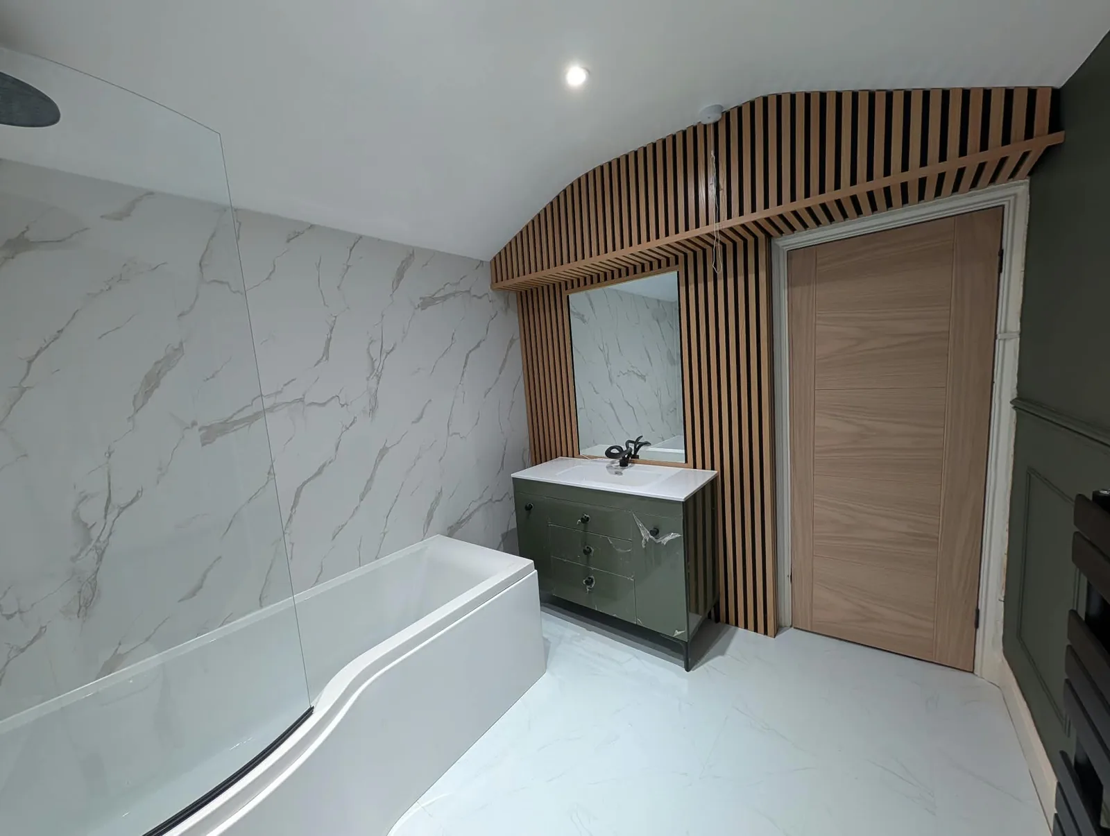 Bathroom with a green vanity, timber slat surround and marble-effect wall panels.