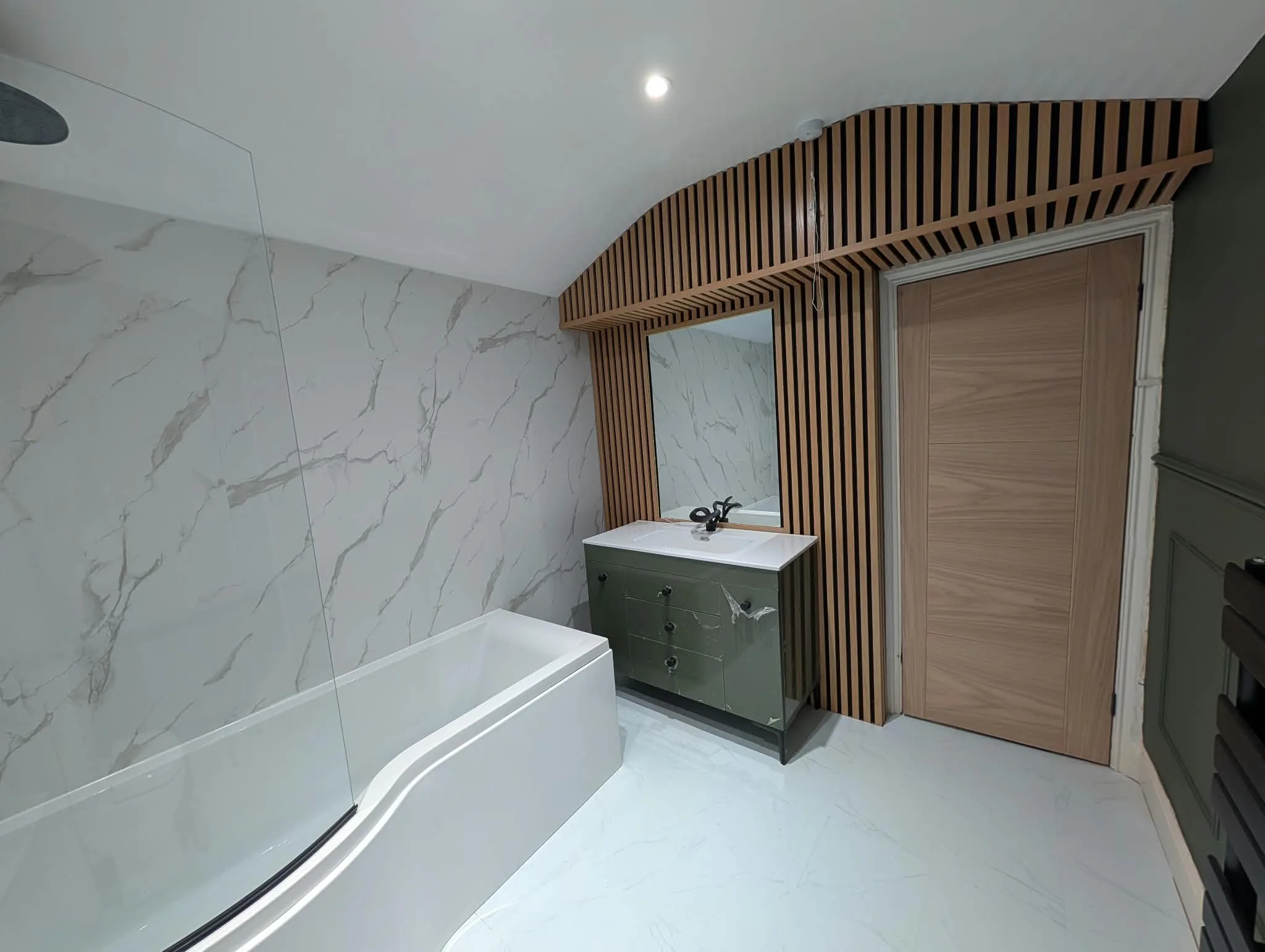 Green vanity and timber slatted wall detail alongside marble-effect bathroom surfaces