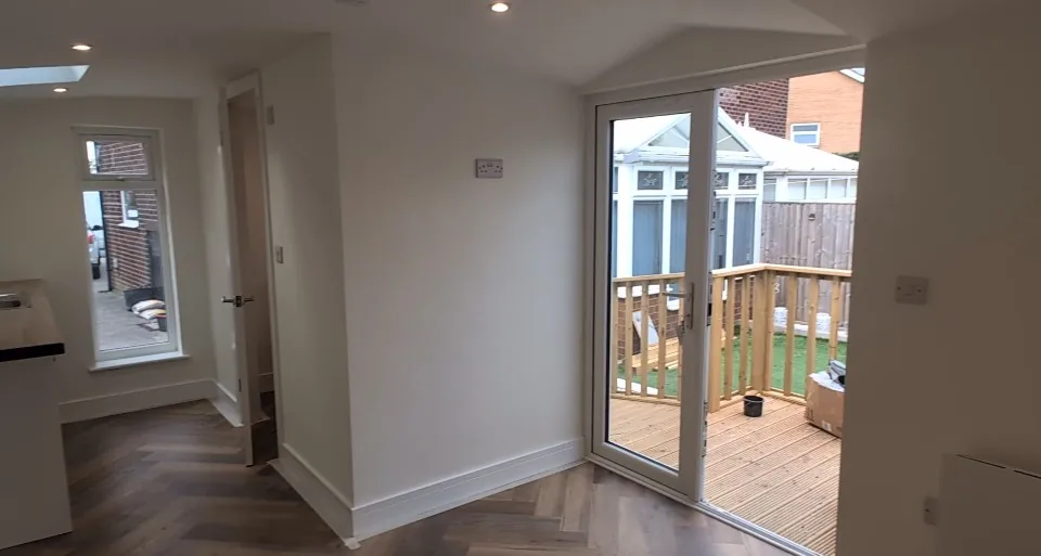 Renovated interior with herringbone flooring and glazed doors opening onto decking