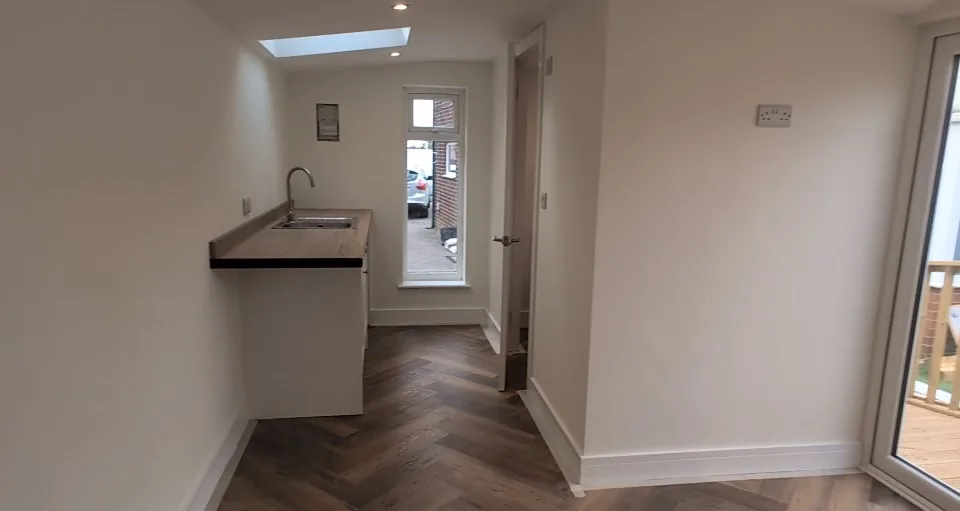 Compact kitchenette under a rooflight beside herringbone flooring.