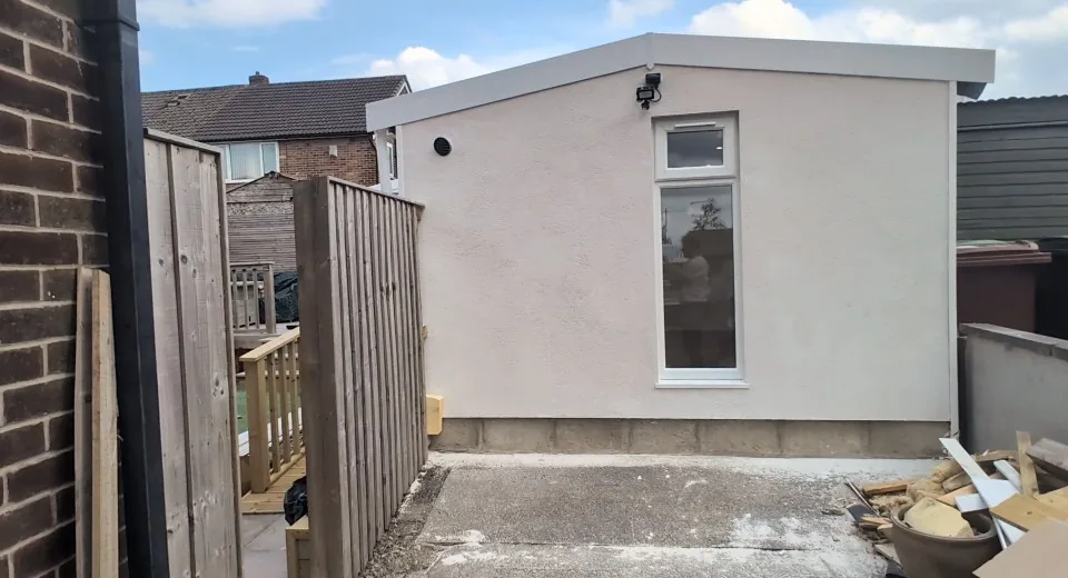 White rendered conversion exterior with a tall window and adjacent decking.