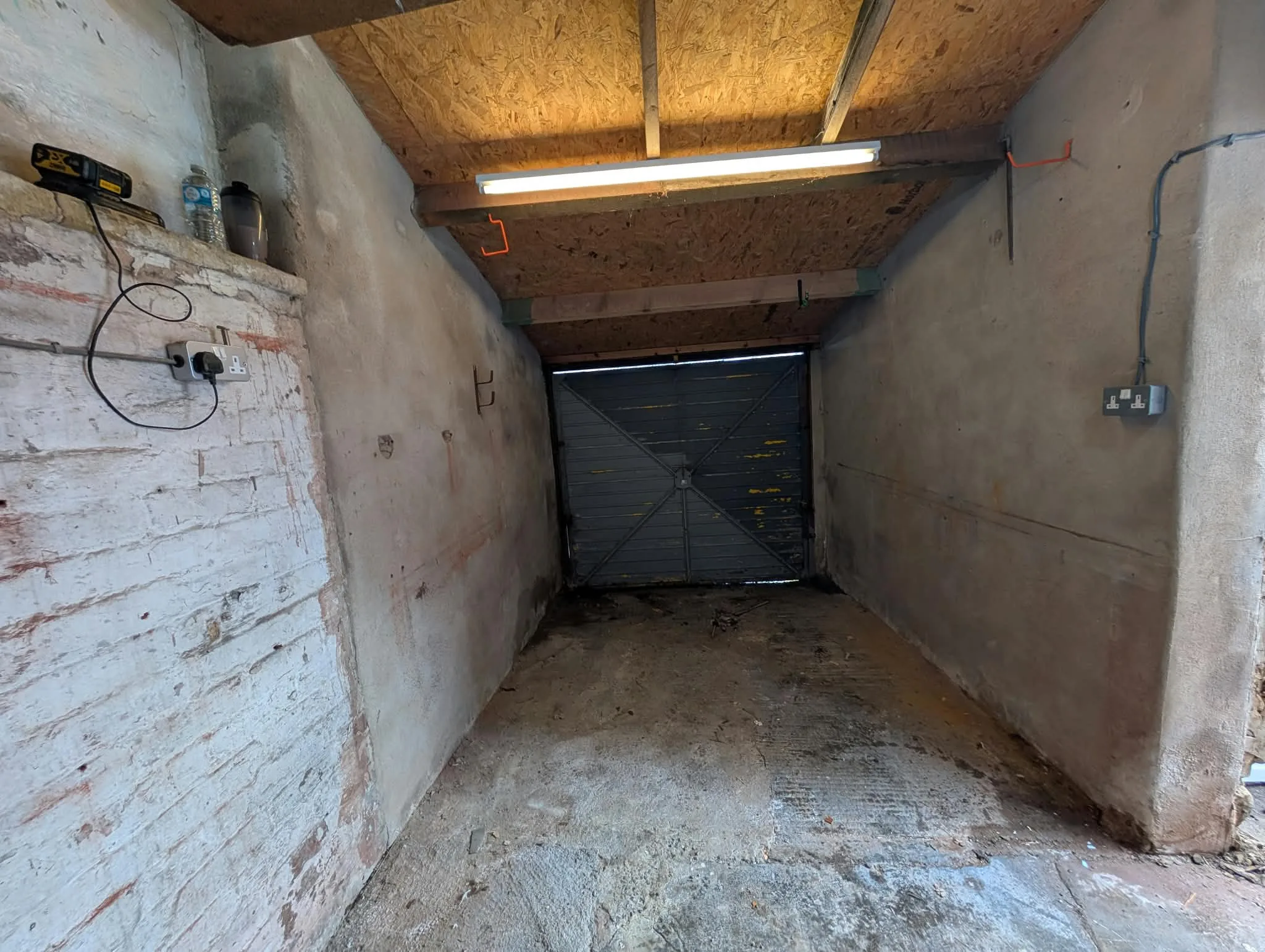 Cleared garage with a concrete floor, whitewashed walls and black doors.