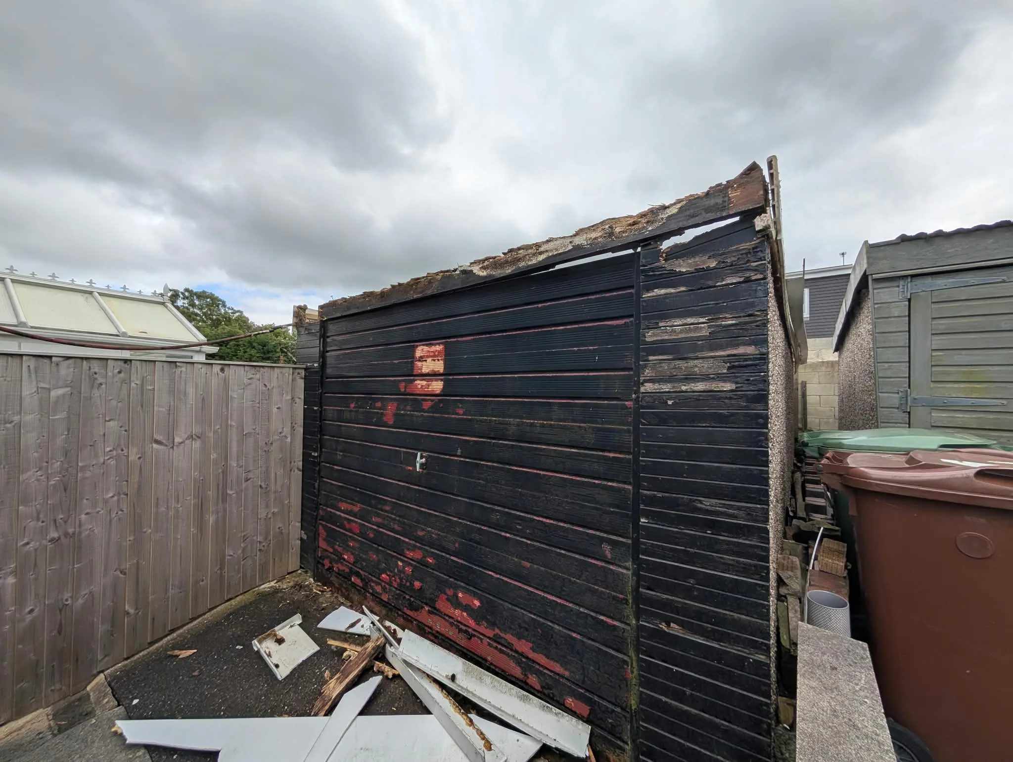 Garage front with old black doors and exposed roof edges during preparation.
