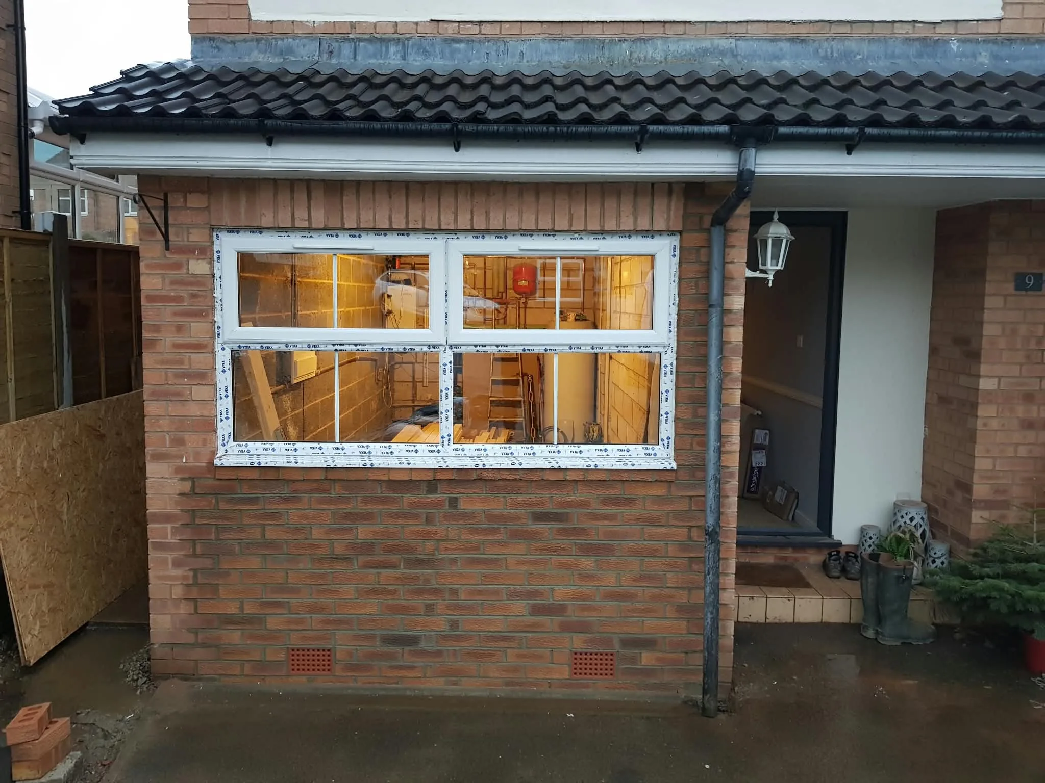 New window and brickwork at a former garage opening, with work continuing inside.