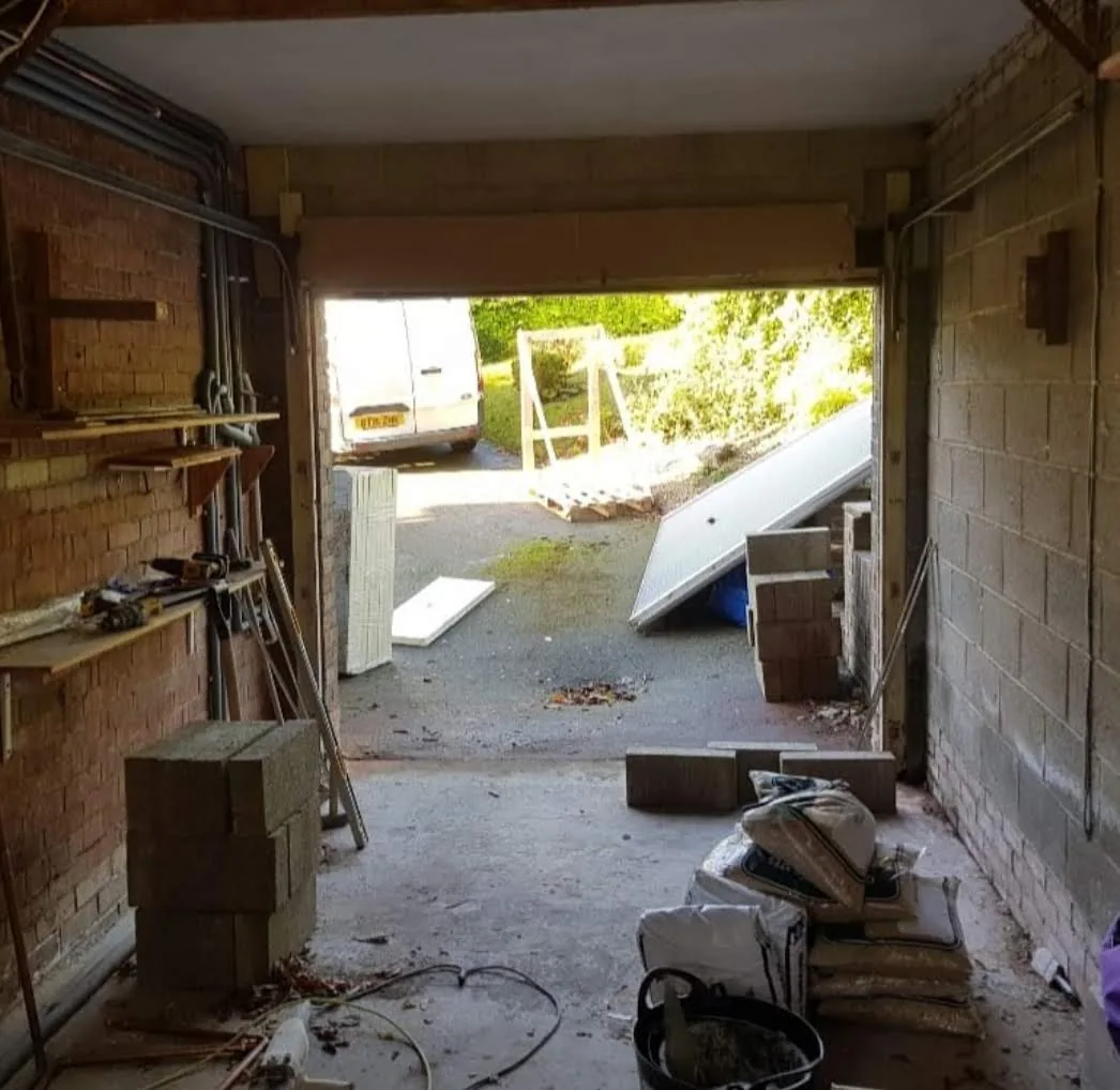 Garage interior with exposed brickwork and materials at the open entrance.