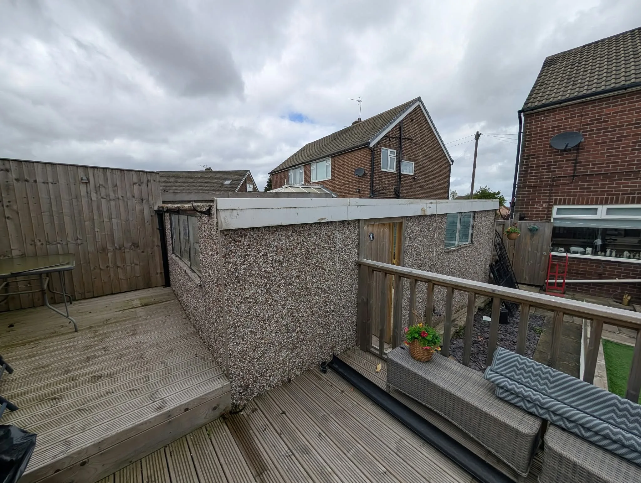Existing pebbledash garage beside a timber deck.