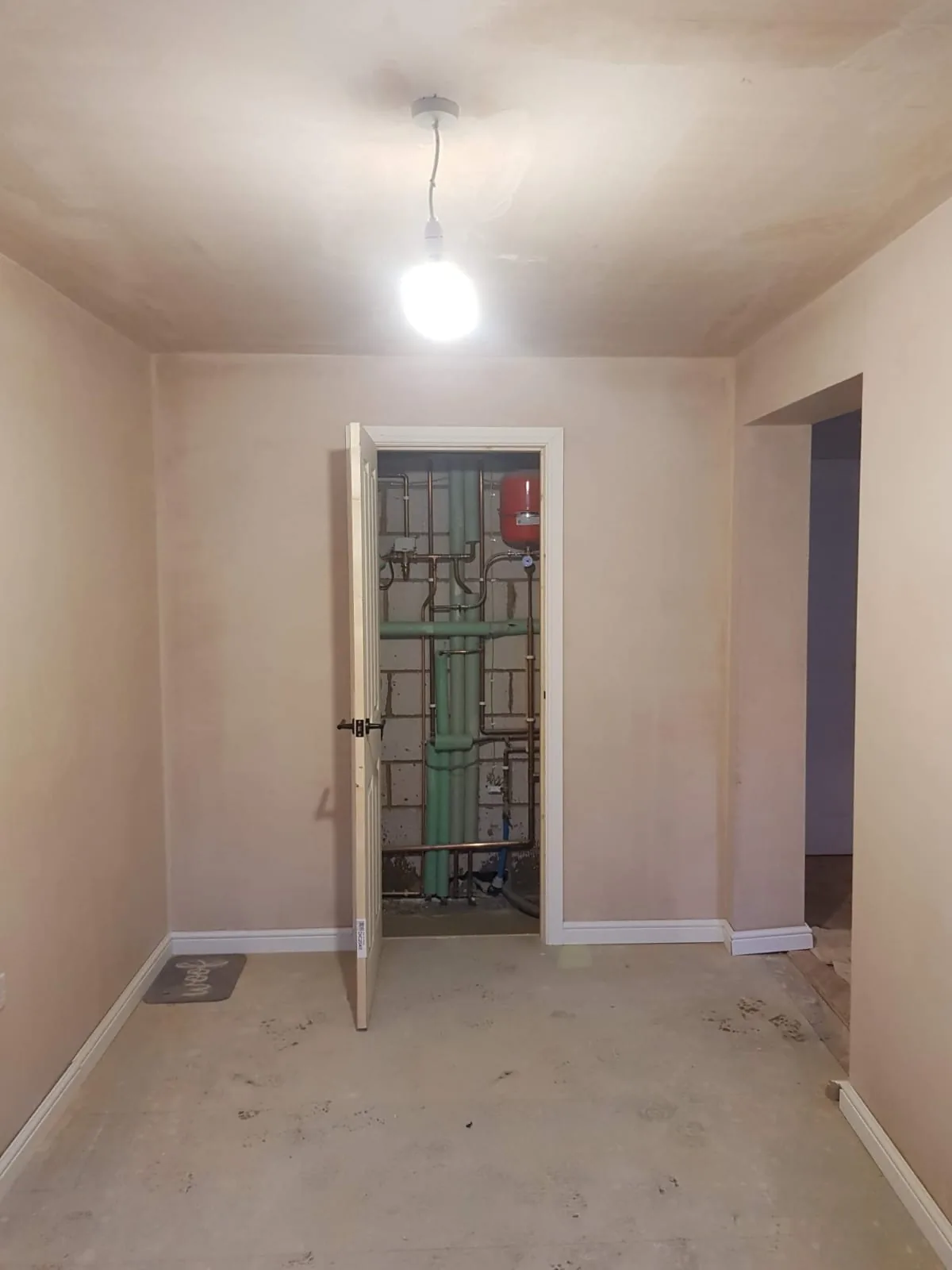 New plaster and a fitted cupboard door, with pipework visible inside.