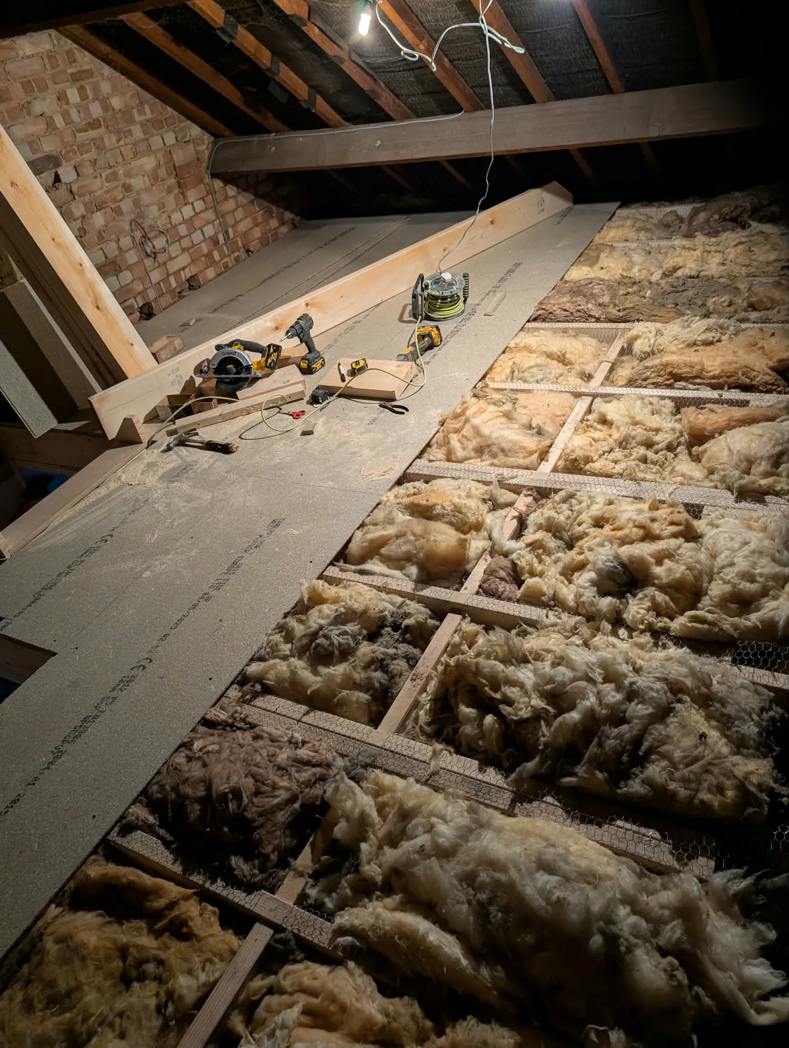 Loft floor with exposed insulation, new boarding and joinery tools.