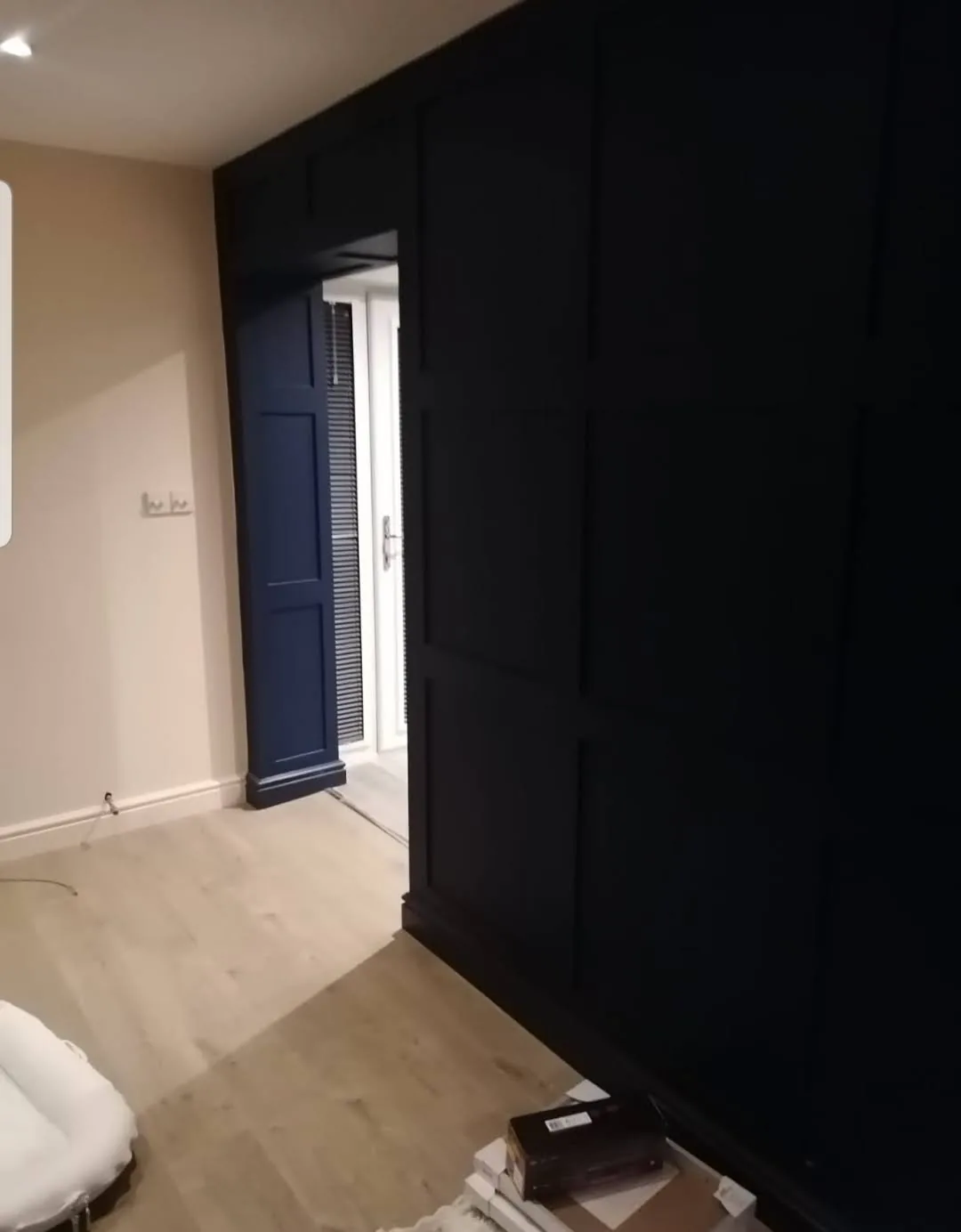 Navy wall panelling around a doorway with wood-effect flooring.