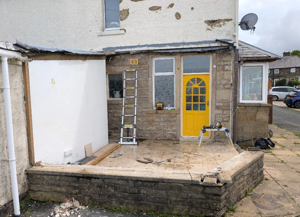 Stone house with a yellow door and exterior renovation work in progress.