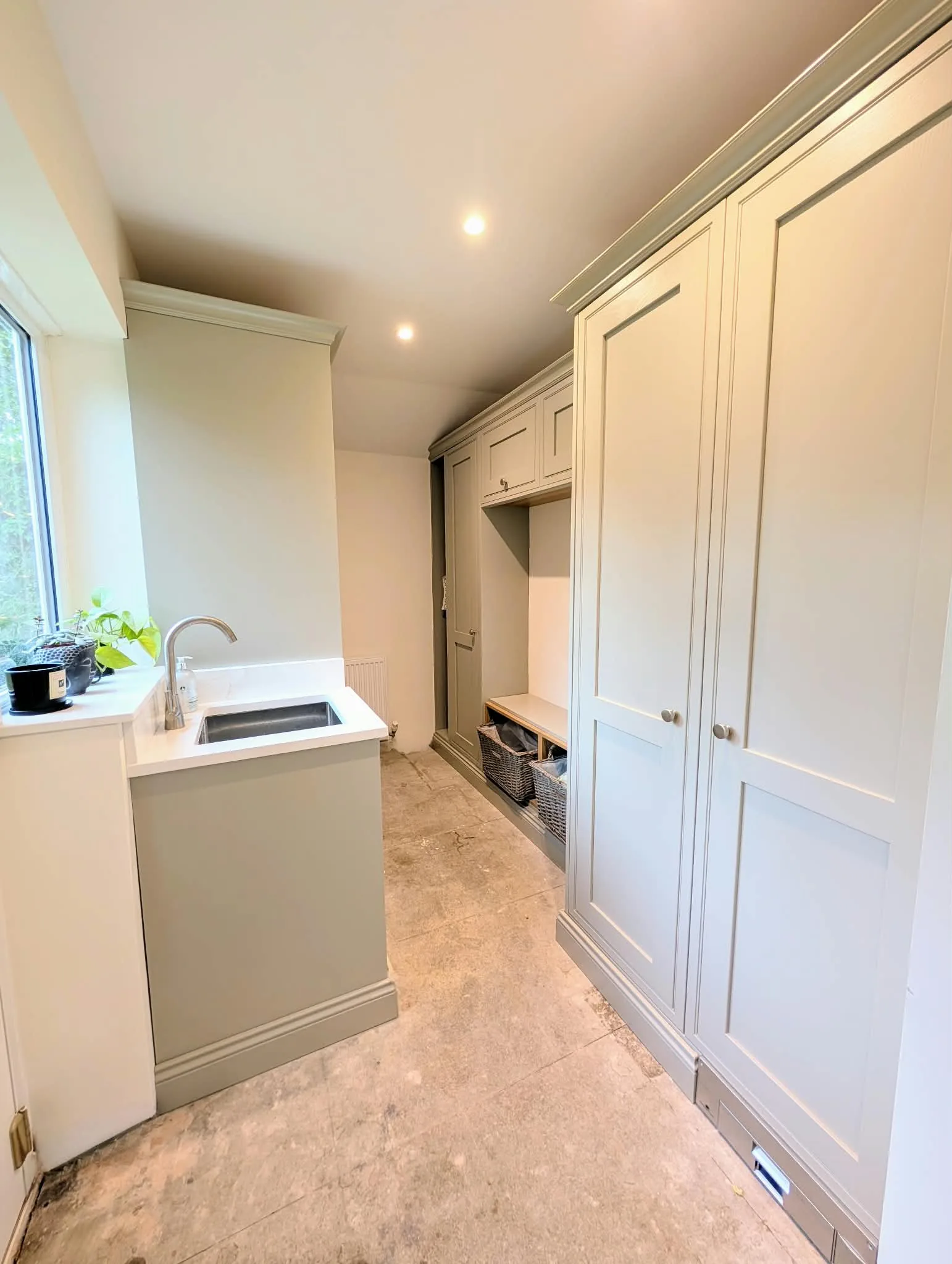 Utility room with floor-to-ceiling cabinetry, a sink and a bench with wicker baskets